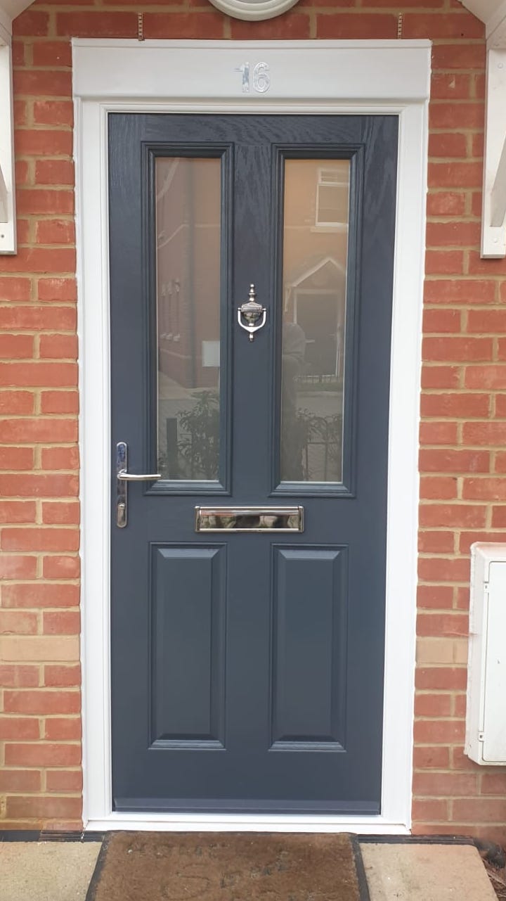 Brick house with a dark blue, almost black composite front door. The door has glass panels and a traditional door knocker.