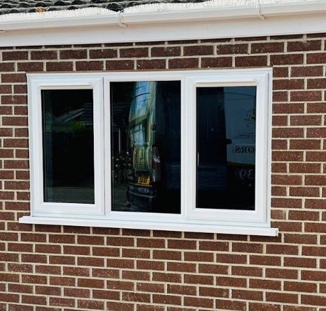 Casement windows on a red brick house. The windows are UPVC and there are three of them.