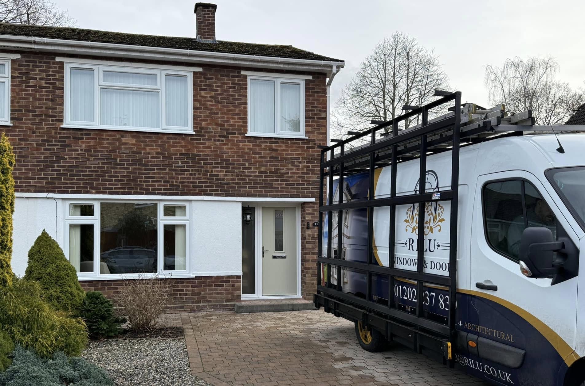 The front of a house with the RILU branded van outside. The house has new white UPVC casement windows.
