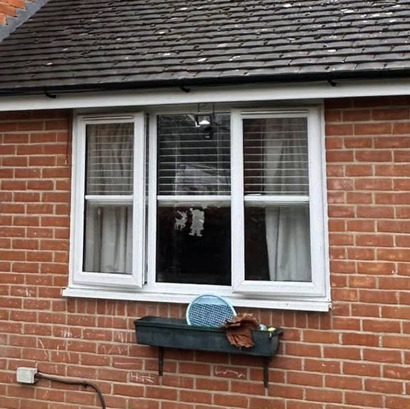 Casement windows on a red brick house with a window box beneath it.