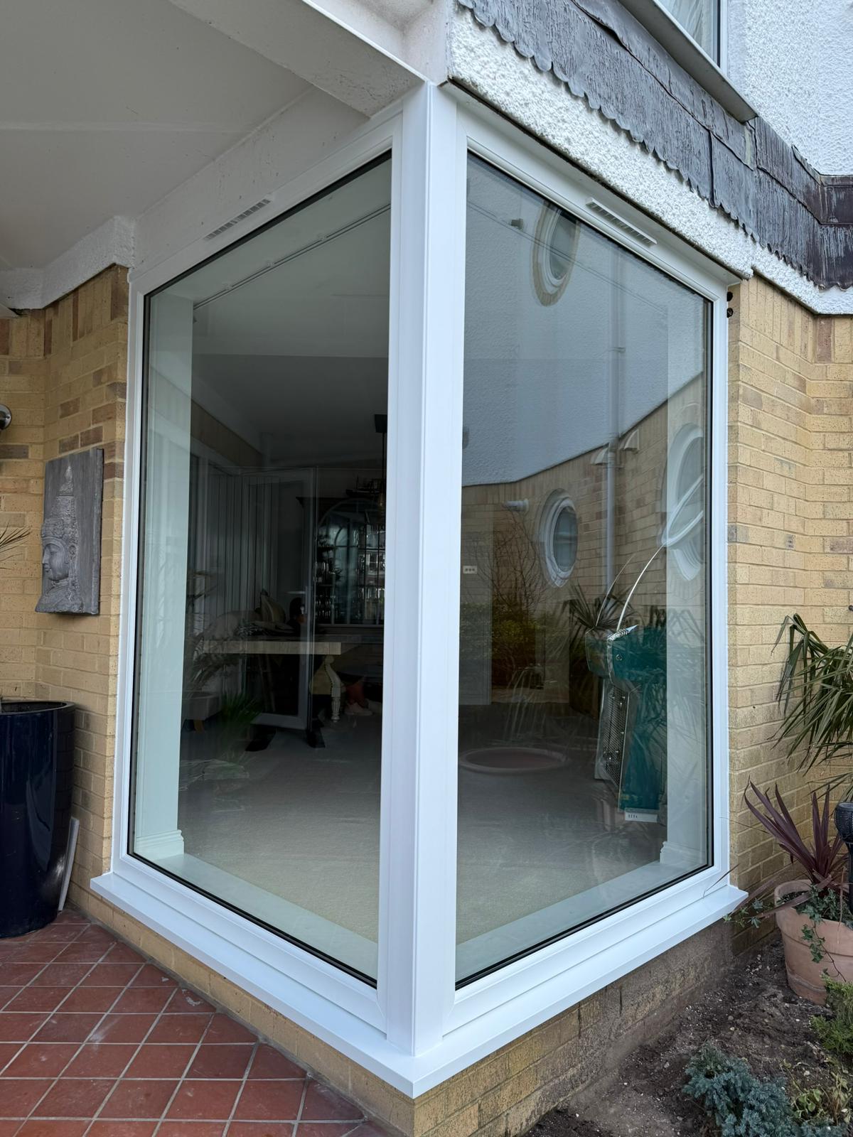 Exterior view of corner bay window with white uPVC frames wrapping around house corner, installed by RILU Windows