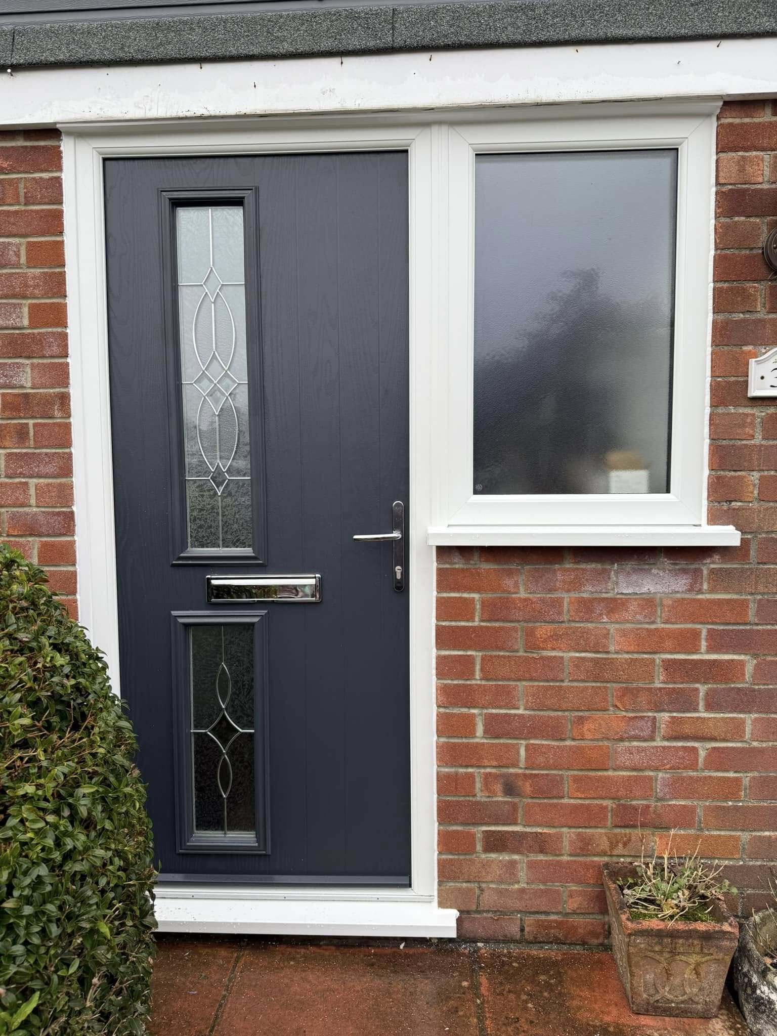 Black front door with obscure glass panel, combining modern style and privacy.