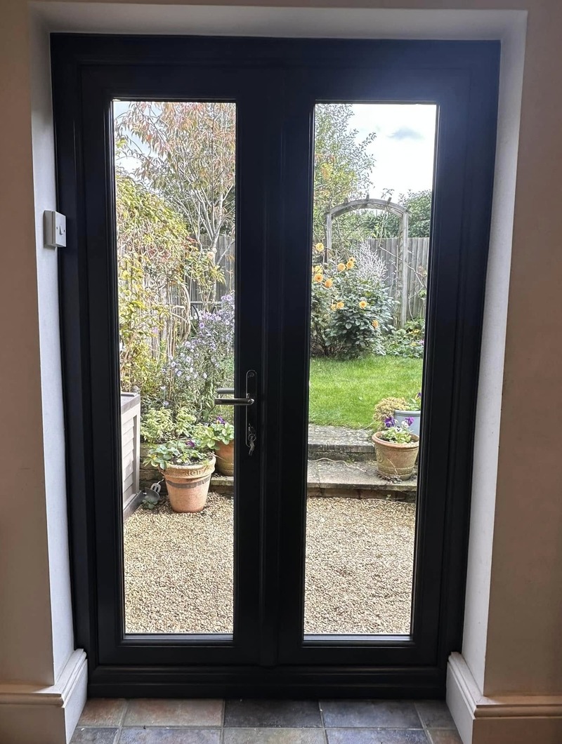 Black french doors showing a garden behind
