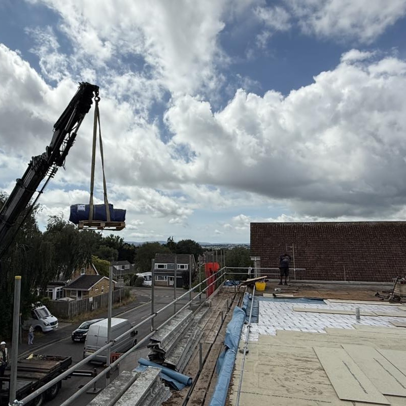 EPDM rubber roof installation in progress with a crane lifting materials onto the roof